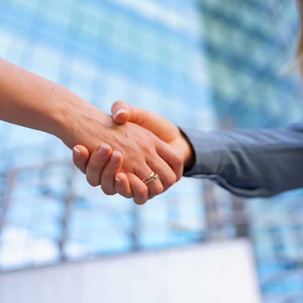 Woman hands shake on business building background Woman handshaking outdoors over modern glass business building background, close-up picture